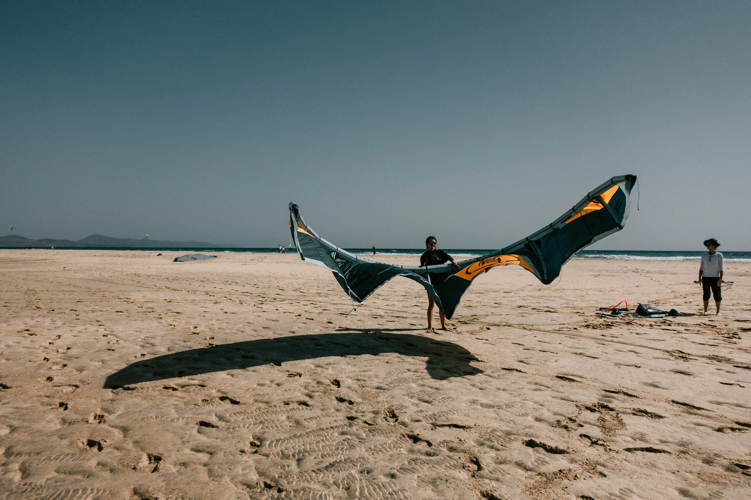 Kiter trägt seinen Kite über den weiten Strand am Indischen Ozean